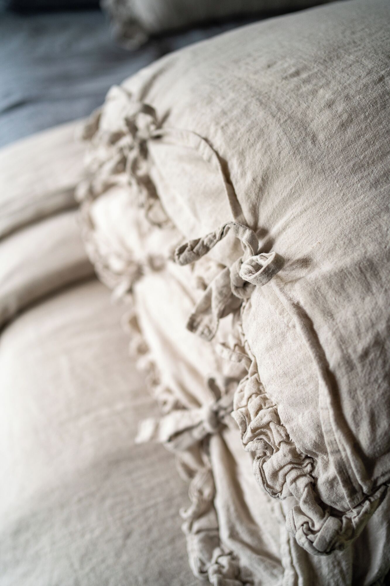 Primer plano de una cama con tela arrugada y un detalle de nudo decorativo.