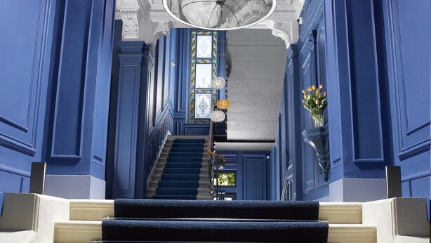 A grand staircase with blue walls and white trim leading to a balcony. - Residence Le Moon (Strasbourg)