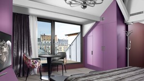 A modern bedroom with a large window, a dining area with a table and chairs, and purple walls. - Residence Le Moon (Strasbourg)