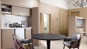 A modern kitchen with a microwave, kettle, and coffee maker. There is a dining table with two chairs and a chandelier. - Residence Le Moon (Strasbourg)