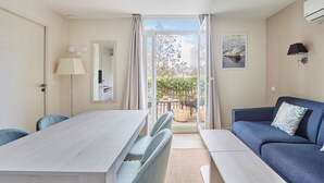 Une pièce moderne comprenant une table à manger, des chaises, un canapé et donnant sur l’extérieur.