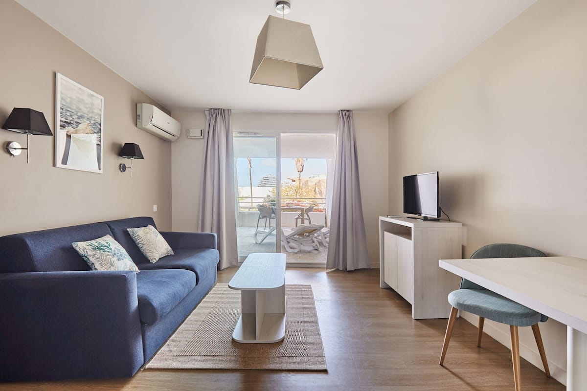 Een moderne woonkamer met een bank, een salontafel, een televisie en een eethoek.