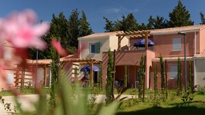 A residential building with multiple balconies, outdoor seating, and a garden area. - Résidence Odalys Le Mas des Alpilles (Paradou)