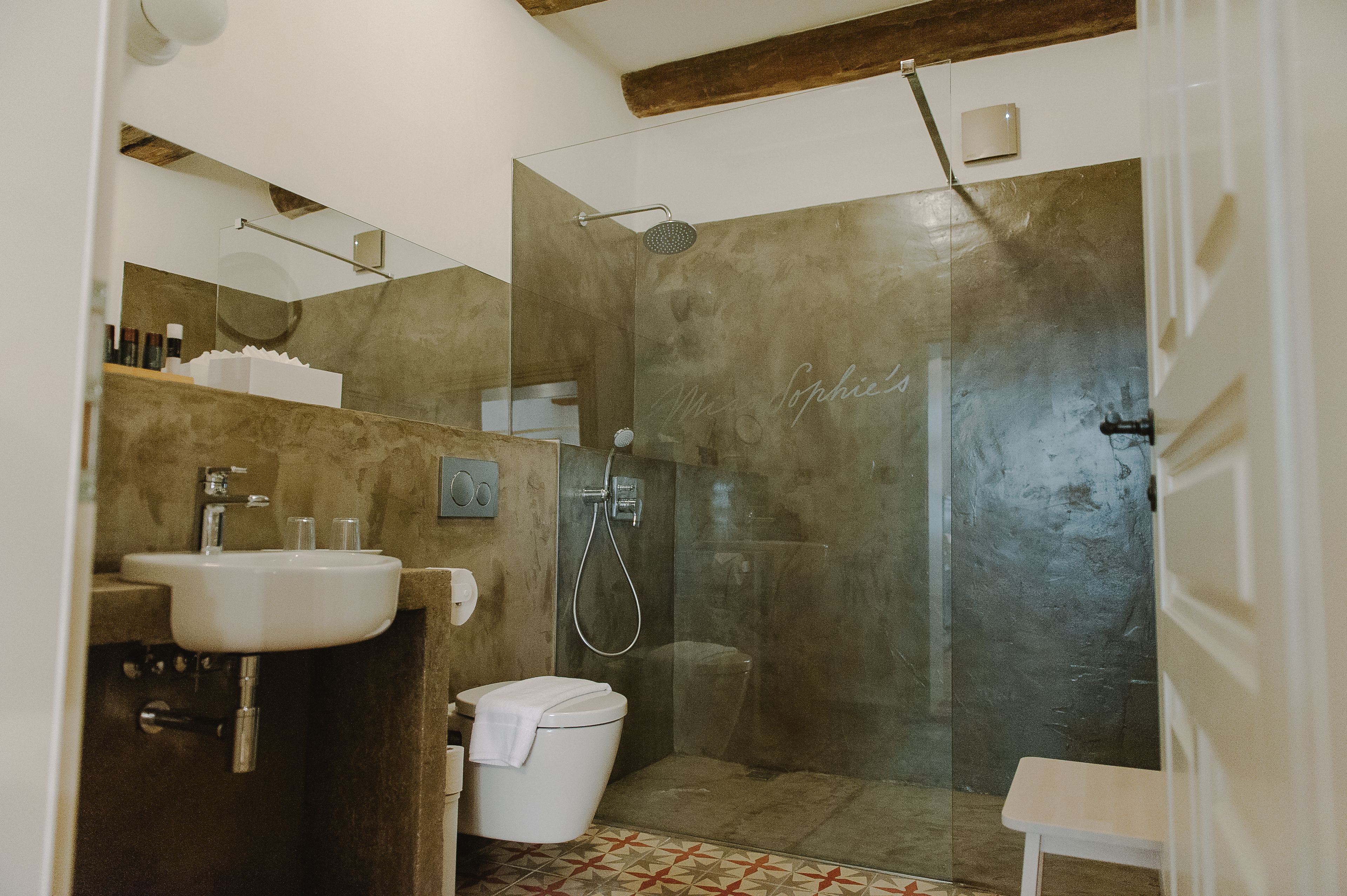 A modern bathroom with a glass-enclosed shower, a sink, and a toilet.