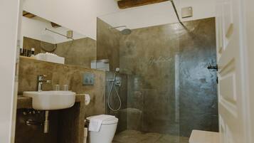 A modern bathroom with a glass-enclosed shower, a sink, and a toilet.