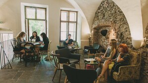 A group of people seated around a table in a room with stone walls and large windows. - Miss Sophie's Olomouc (Olomouc)