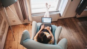 A person lying on a chair with a laptop, in a room with wooden flooring and a window with curtains. - Miss Sophie's Olomouc (Olomouc)