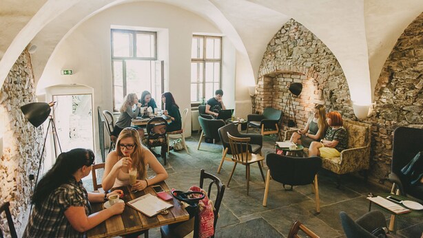 A cozy cafe with stone arches, wooden furniture, and a stone fireplace. - Miss Sophie's Olomouc (Olomouc)