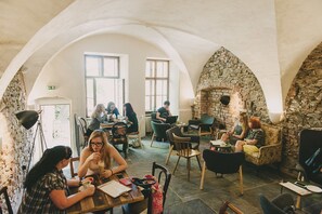 Um café acolhedor com arcos de pedra, móveis de madeira e lareira de pedra.