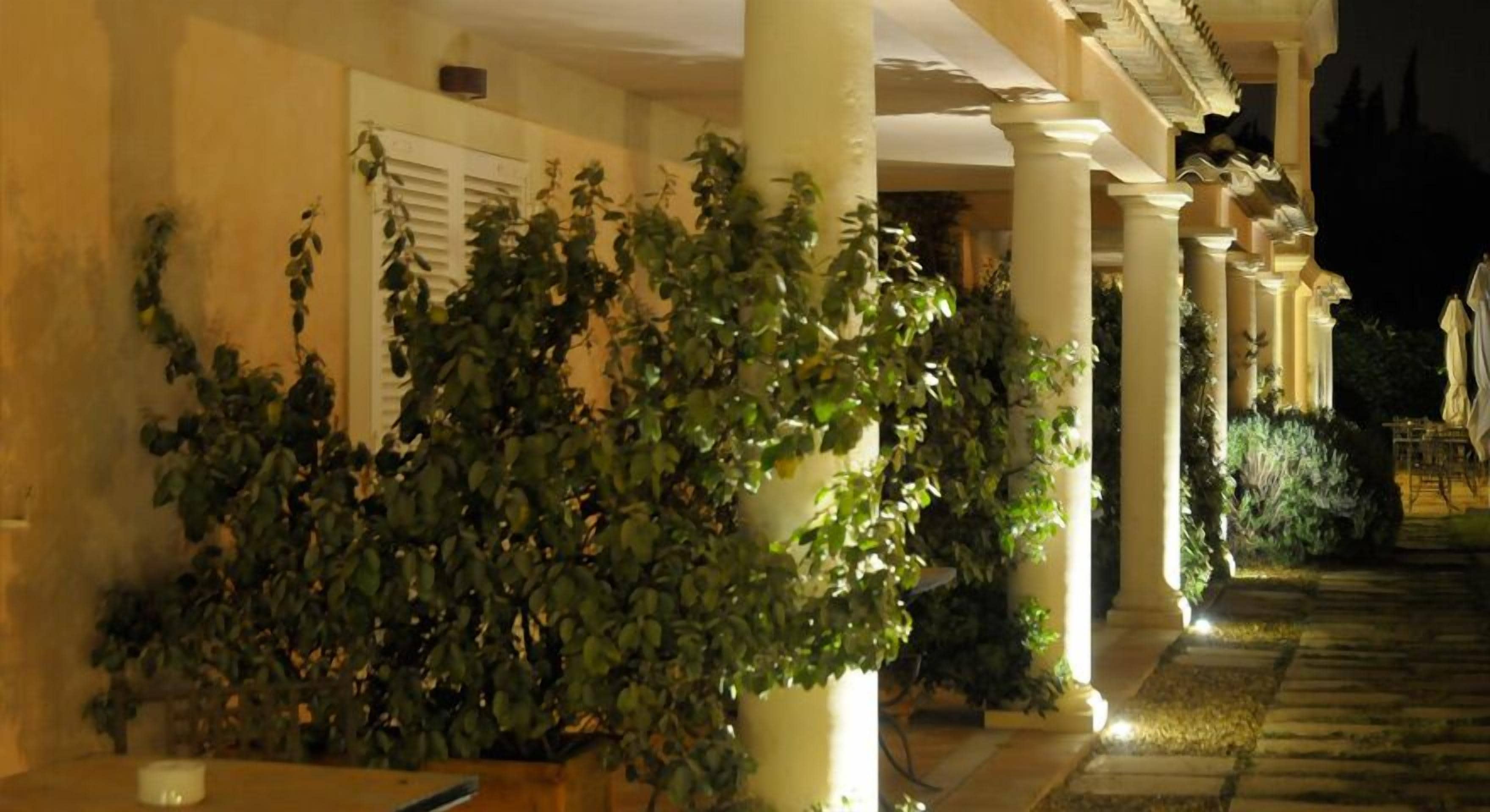 A covered outdoor area with columns and potted plants.