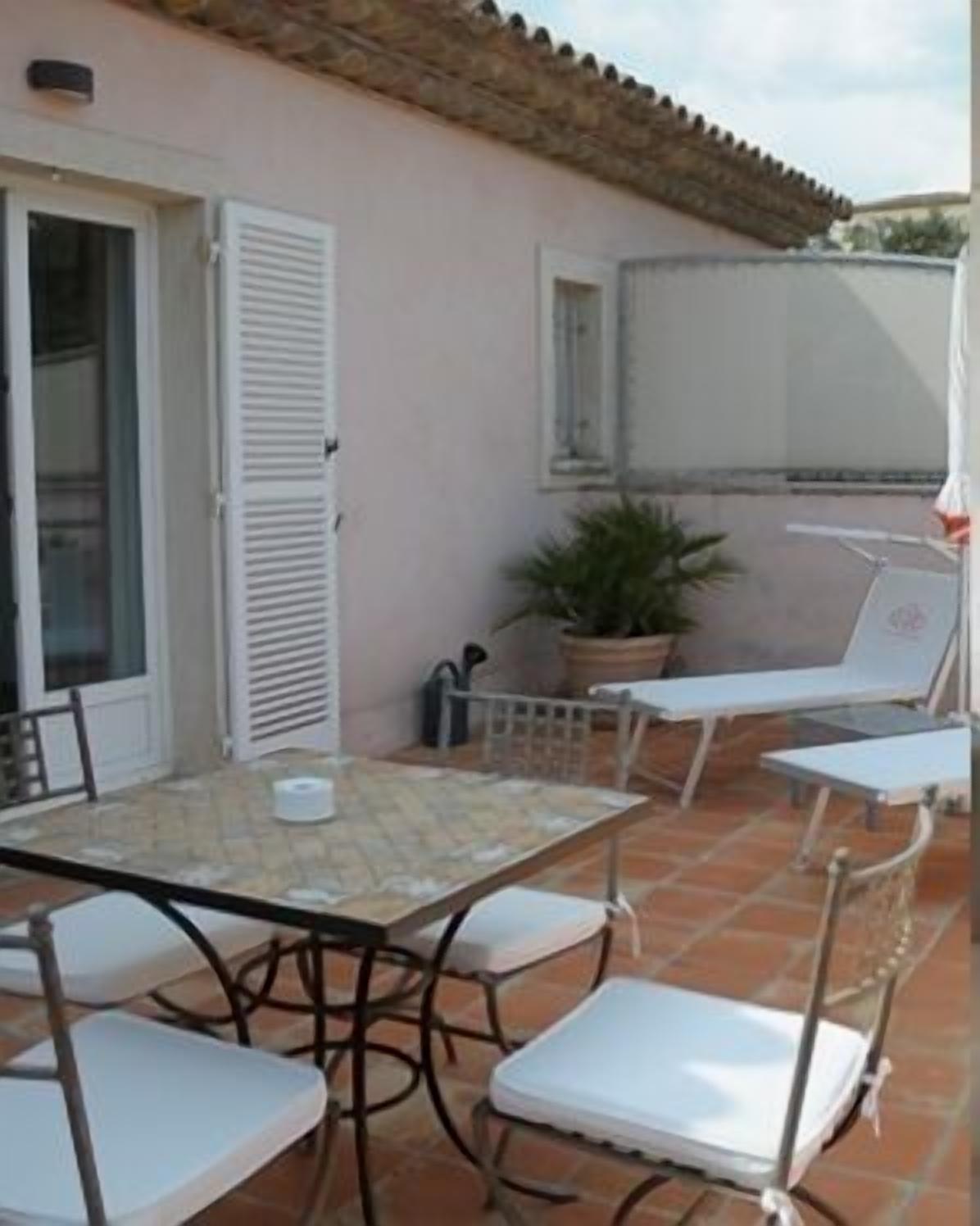 Eine Außenpatio mit Tisch und Stühlen, einem Blumentopf und einer überdachten Sitzgelegenheit.