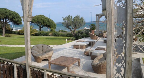 An outdoor seating area with wicker furniture, a pergola, and a view of the sea. - Hôtel Villa Les Rosiers (Grimaud)