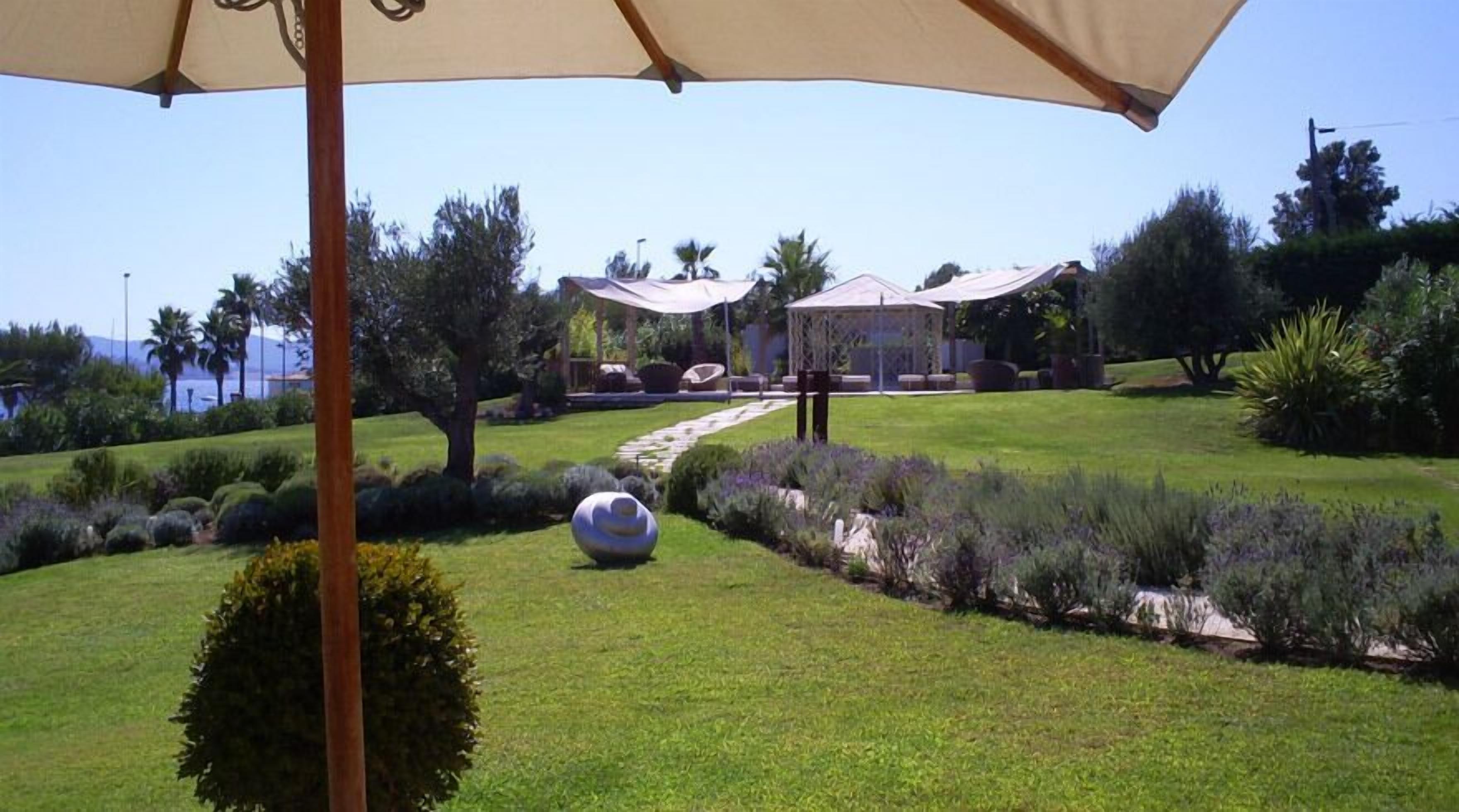A well-maintained garden with a gazebo, a clear pathway, and a view of the sea.