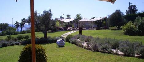 A well-maintained garden with a gazebo, a clear pathway, and a view of the sea.