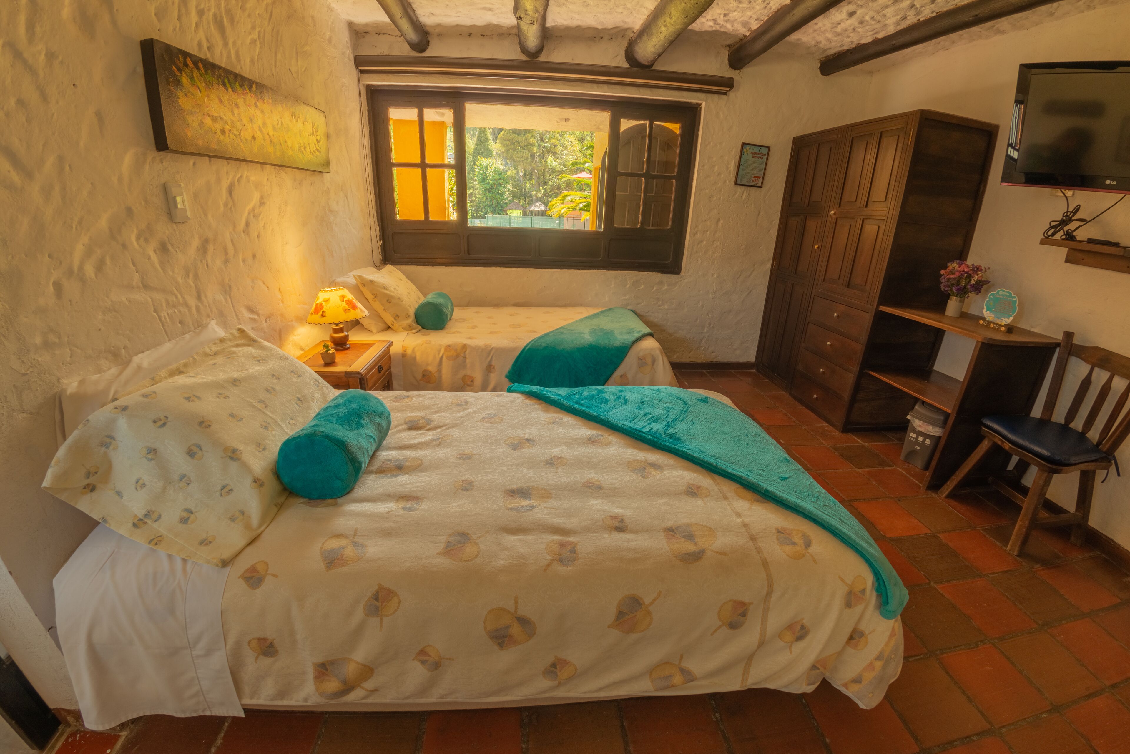 Un dormitorio con dos camas, una ventana con vistas, un televisor y un armario de madera.