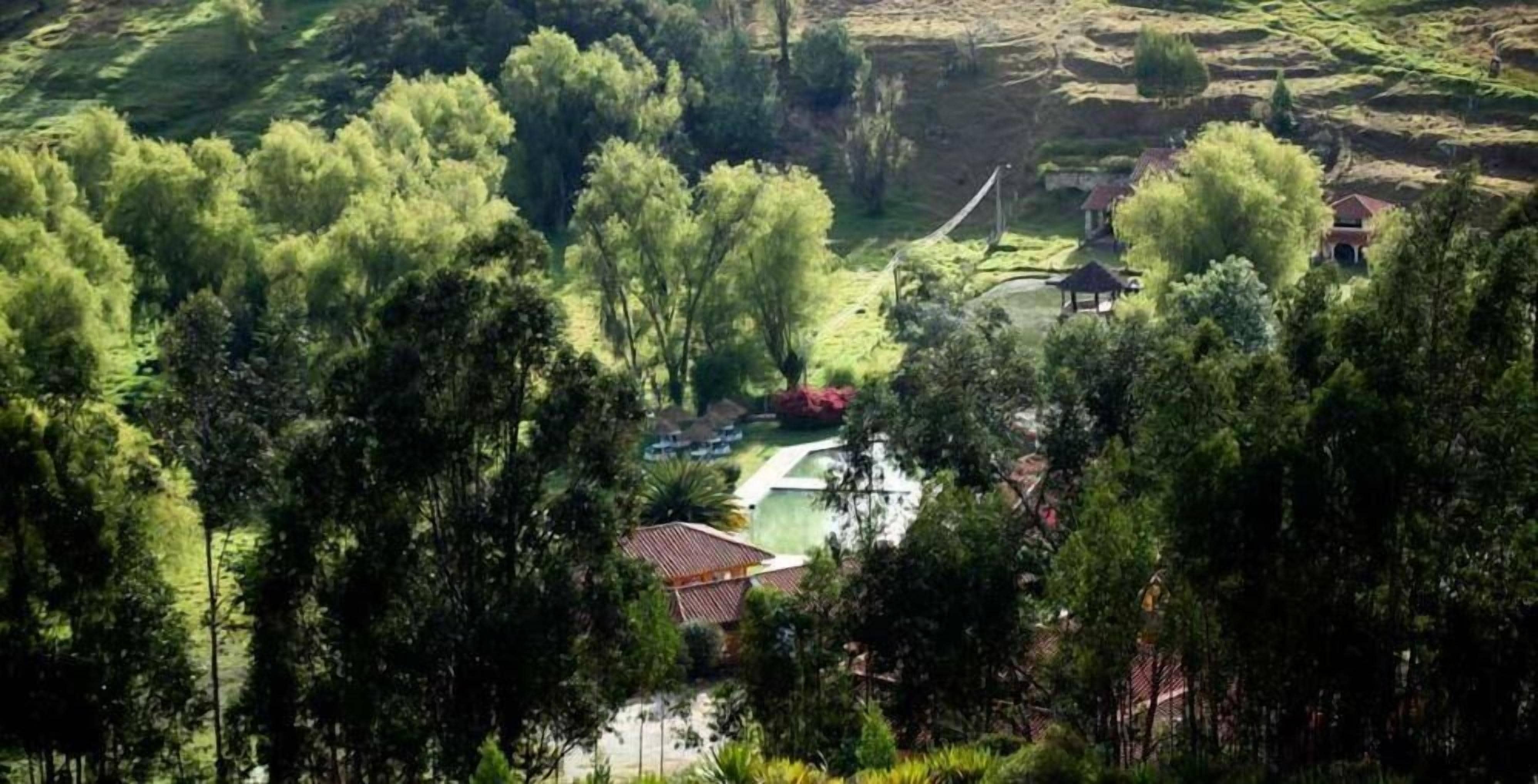 A rural landscape with a gazebo, a small building, and a pathway.