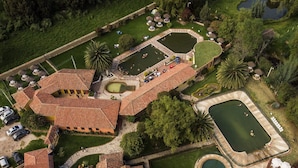 An aerial view of a resort with multiple buildings, a swimming pool, and a landscaped garden. - Hotel Termales El Batán (Cuitiva)