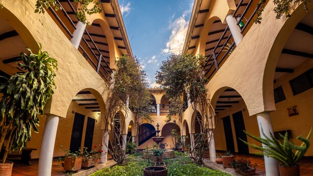 A courtyard with arches, potted plants, and a central fountain. - Hotel Termales El Batán (Cuitiva)