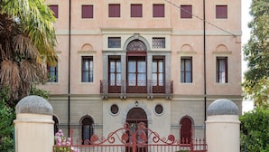 Um edifício com fachada rosa, janelas em arco e varanda decorativa.