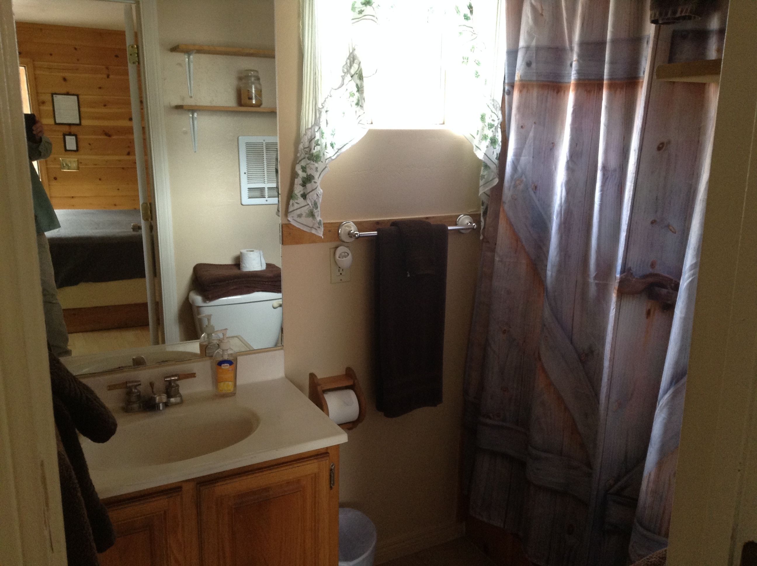 A bathroom with a wooden vanity, a toilet, a sink, and a shower curtain.