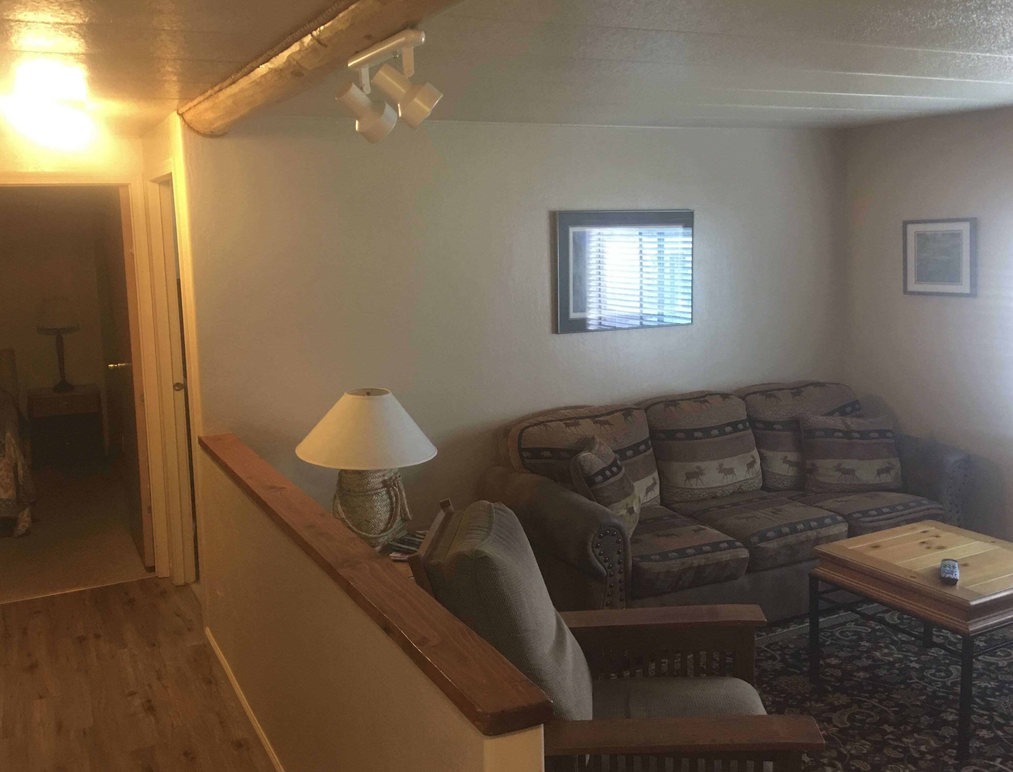 A living room with a sofa, a lamp, a window, and a small table.