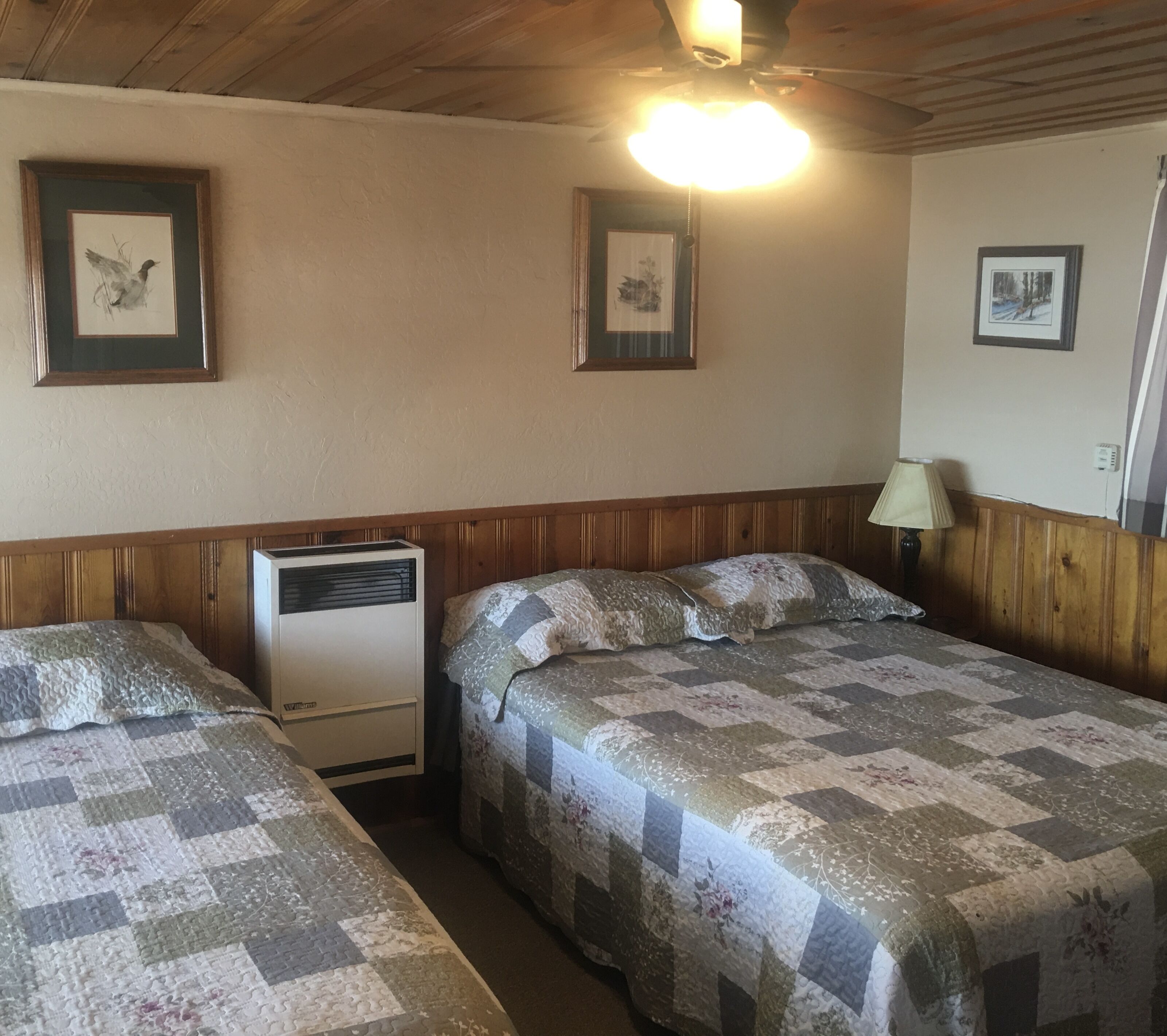 Une chambre avec deux lits, un radiateur et des tableaux encadrés accrochés au mur.