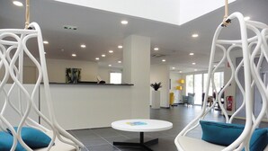 A lobby with hanging chairs, a reception desk, and a round table. - Apartment in France with Furnished Terrace (Cap d'Agde)