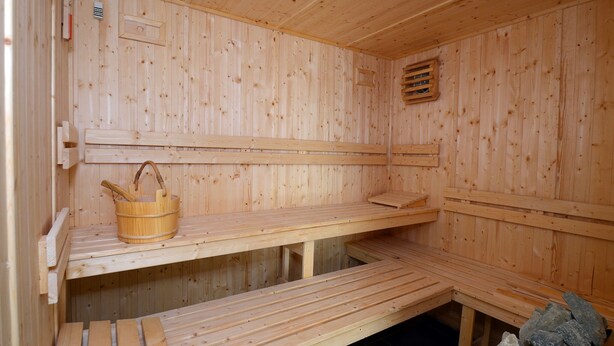 A sauna with wooden benches and a stone-filled container. - Apartment in France with Furnished Terrace (Cap d'Agde)