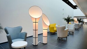A modern lobby with seating areas, a high ceiling, and a visible plant. - Apartment in France with Furnished Terrace (Cap d'Agde)