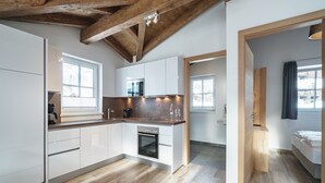 A modern kitchen with white cabinets, a built-in oven, and a coffee maker. There are windows providing natural light and a view of the outside. - Chalet in Piesendorf near Ski Slopes (Piesendorf)
