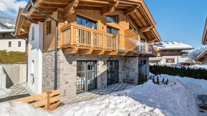 A modern chalet with a stone facade, wooden balcony, and a snow-covered landscape. - Chalet in Piesendorf near Ski Slopes (Piesendorf)