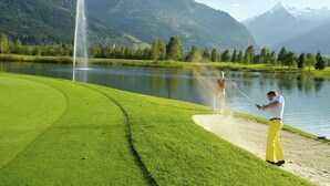 A golf course with a fountain, a lake, and mountains in the background. - Chalet in Piesendorf near Ski Slopes (Piesendorf)