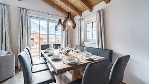 A dining area with a wooden table set for six, black chairs, and pendant lights. - Chalet in Piesendorf near Ski Slopes (Piesendorf)