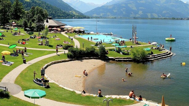 A lakeside resort with a swimming pool, sun loungers, and a grassy deck. - Chalet in Piesendorf near Ski Slopes (Piesendorf)