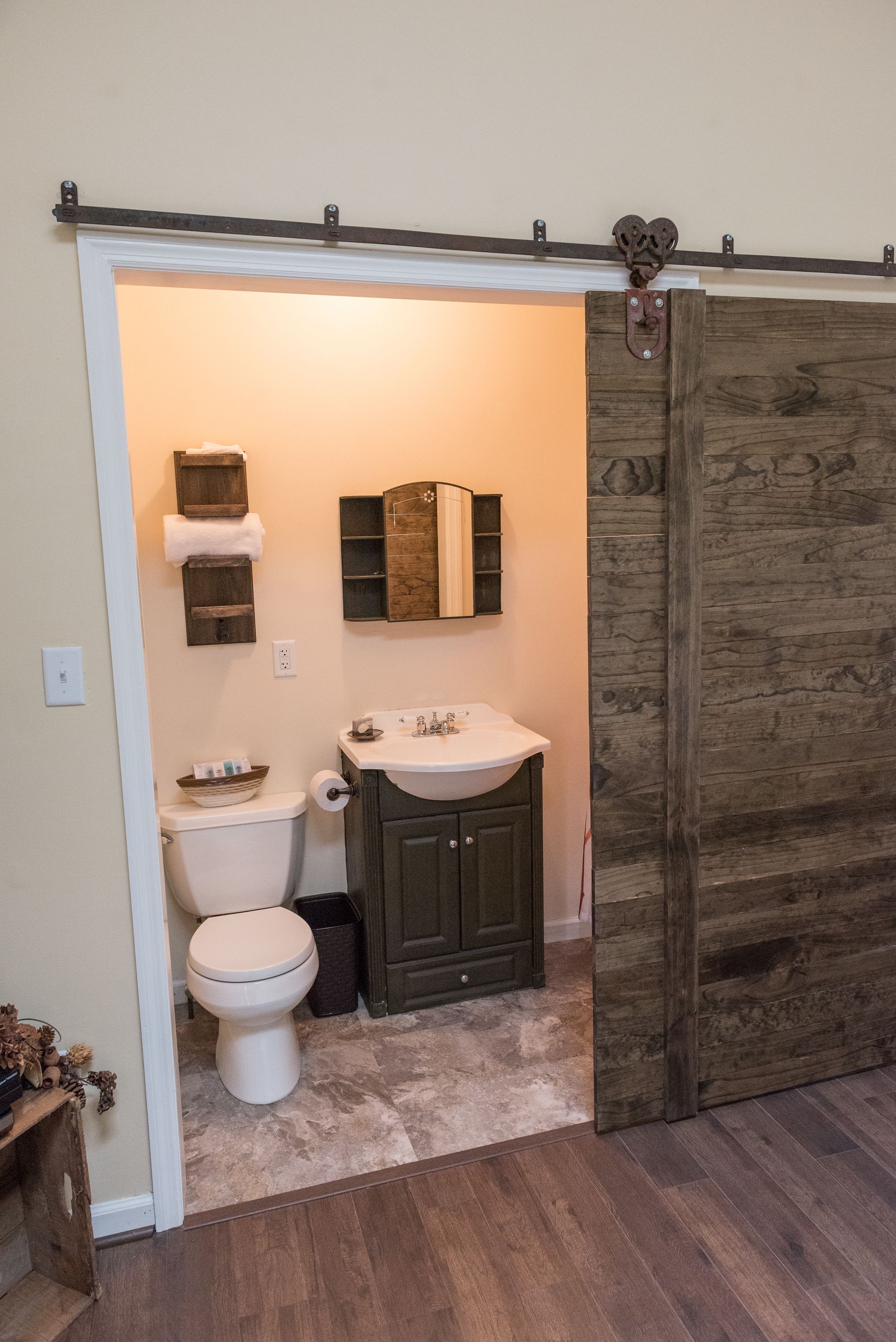 A bathroom with a toilet, sink, and wooden cabinet.
