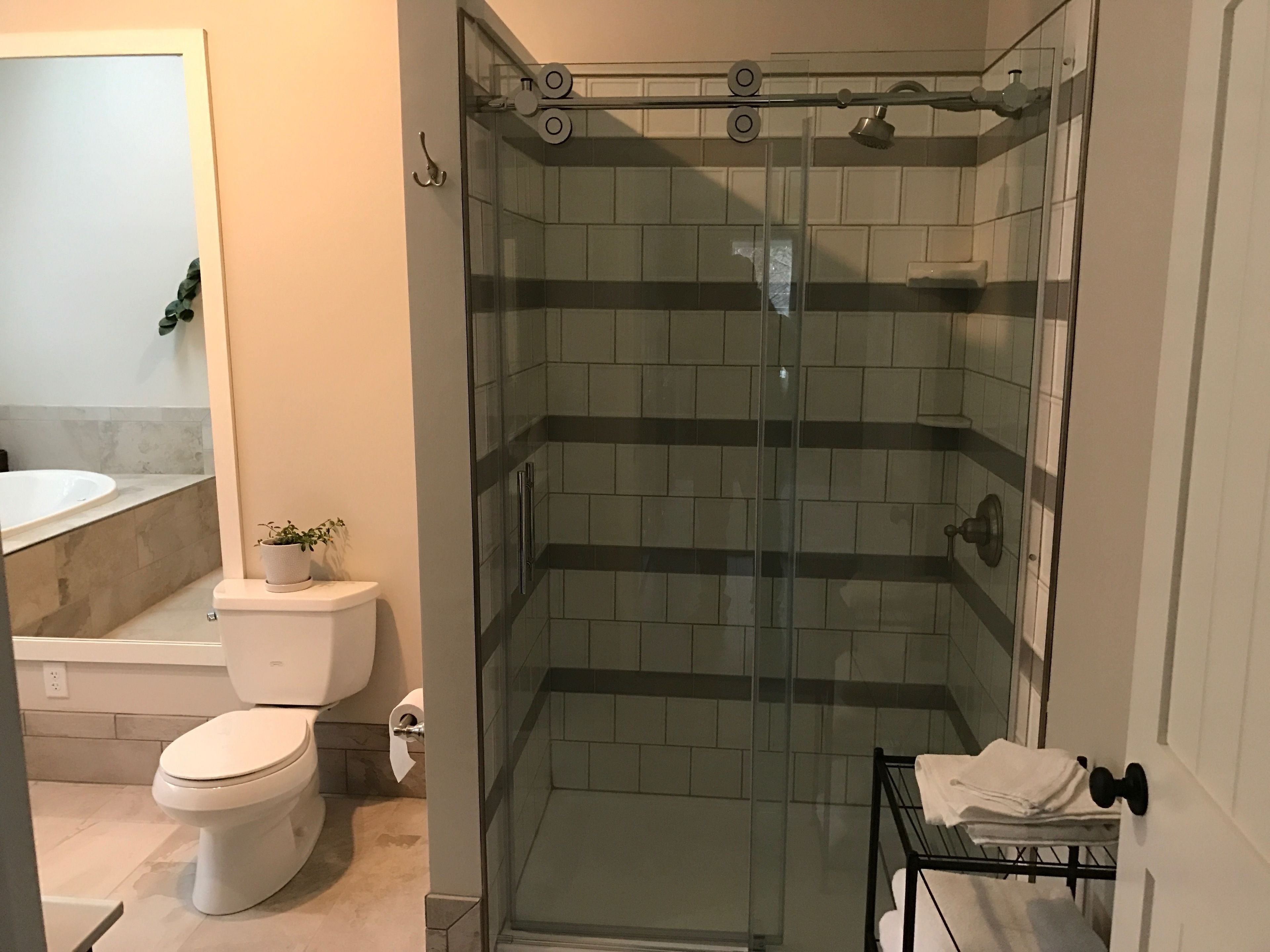 Baño con ducha de vidrio, inodoro y lavamanos.