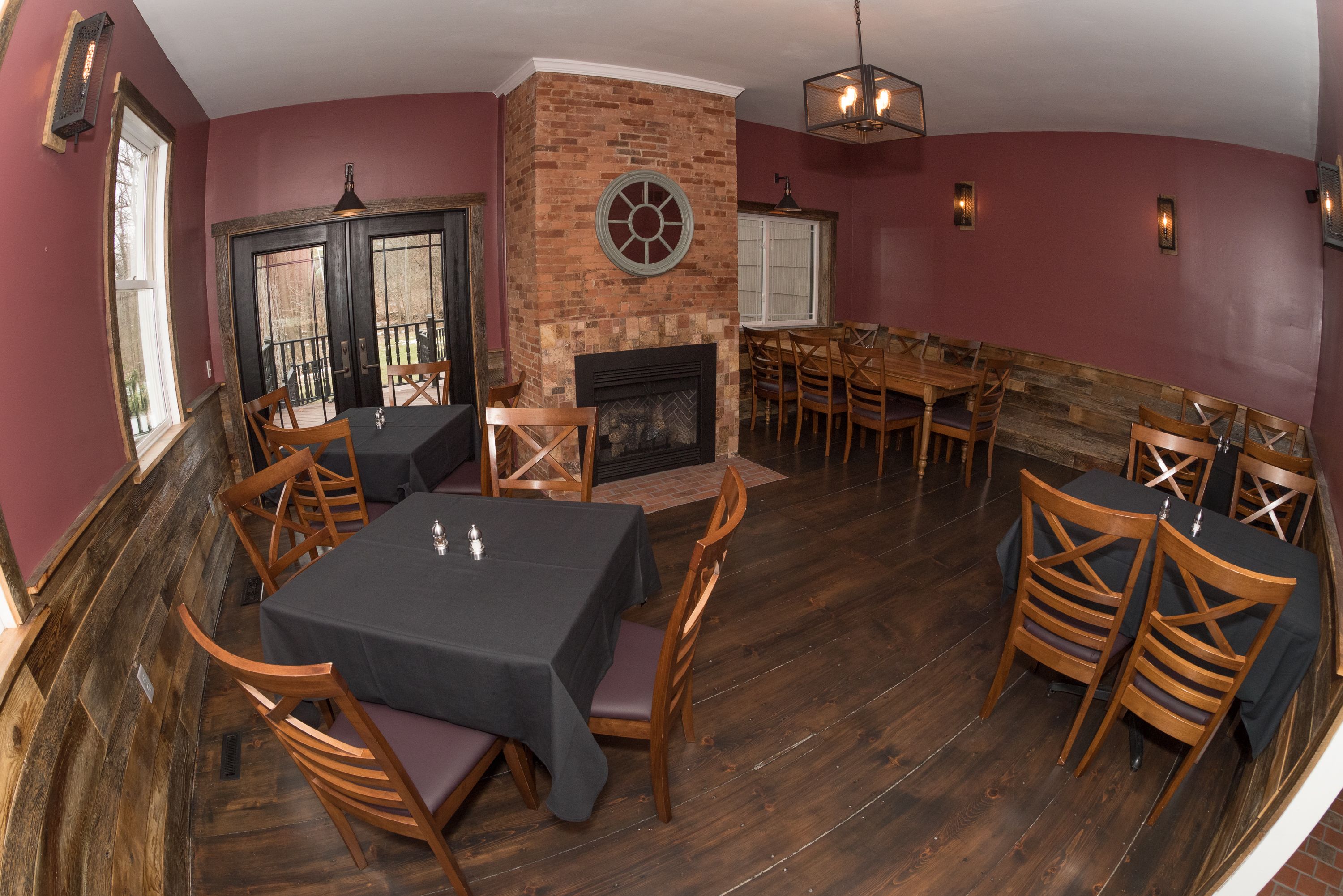 Un ristorante con un camino in mattoni, tavoli e sedie in legno e un'ampia finestra.
