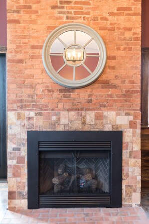 A fireplace with a round window above it, set in a brick wall.