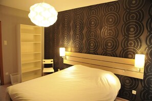 A hotel room with a bed, a white headboard, a wall with circular patterns, and two bedside lamps. - Holiday Home in Marche-en-Famenne near Train (Marloie)