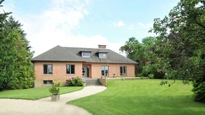 A two-story brick house with a sloped roof, a front porch, and a well-maintained lawn. - Holiday Home in Marche-en-Famenne near Train (Marloie)