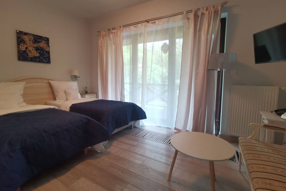 Habitación de hotel con dos camas, una mesita redonda pequeña, una silla, un televisor y un radiador.