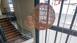 Un interior de varios niveles con una escalera, un conjunto de sofás e iluminación colgante de fibras.