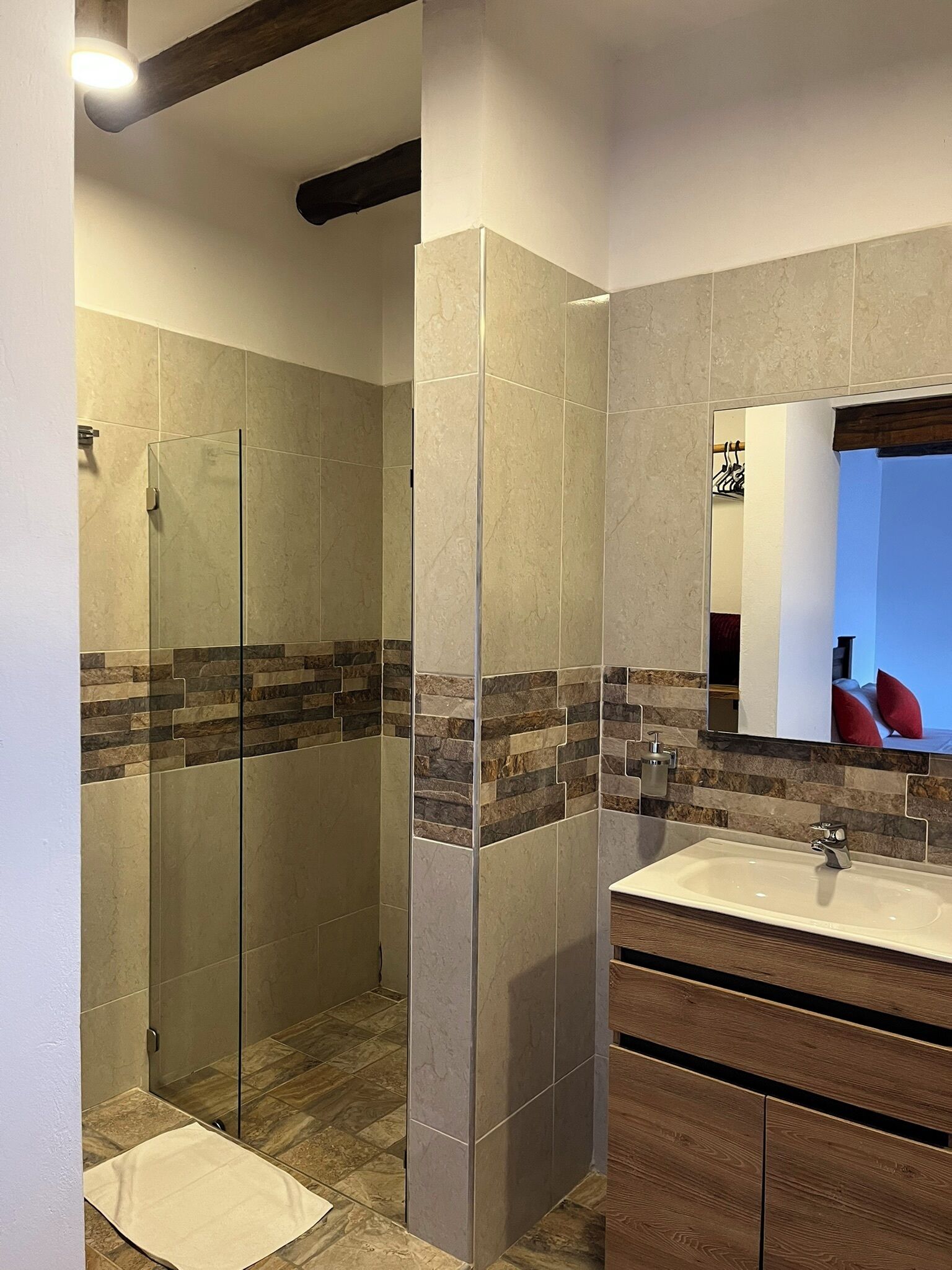 Un baño moderno con cabina de ducha de vidrio, tocador de madera y un espejo grande.