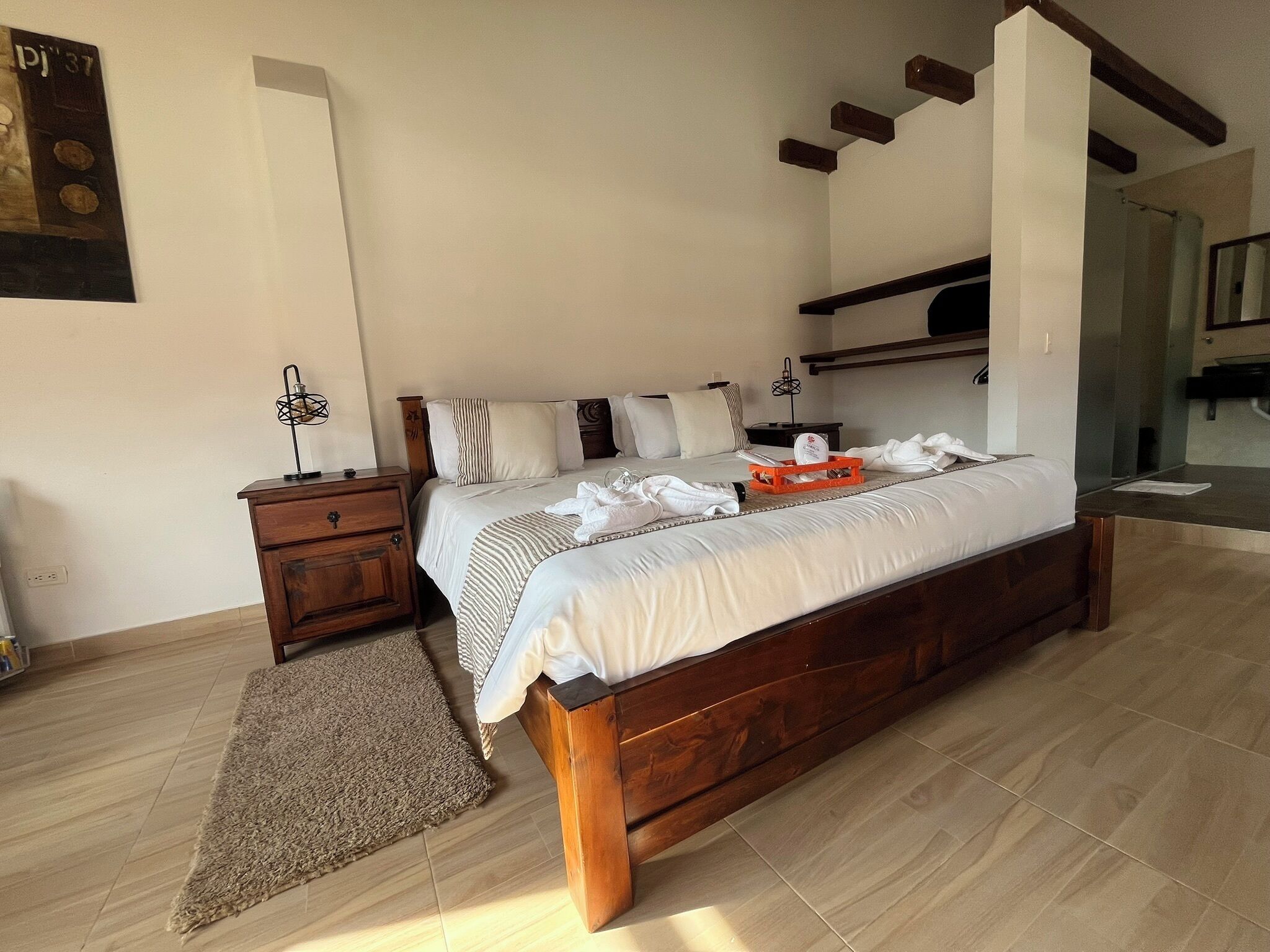 Une chambre à coucher avec un lit en bois, une table de chevet, une commode, un tapis et une étagère fixée au mur.