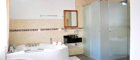 Un baño moderno con una bañera independiente, cabina de ducha con mampara de vidrio y salpicadero de azulejos.