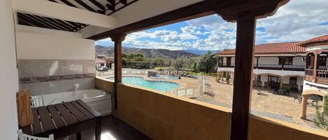 A balcony with a view of a swimming pool and surrounding buildings.