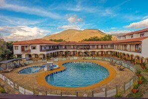 A hotel with a central swimming pool, multiple balconies, and a mountainous backdrop. - Hotel Gran Sirius (Sáchica)
