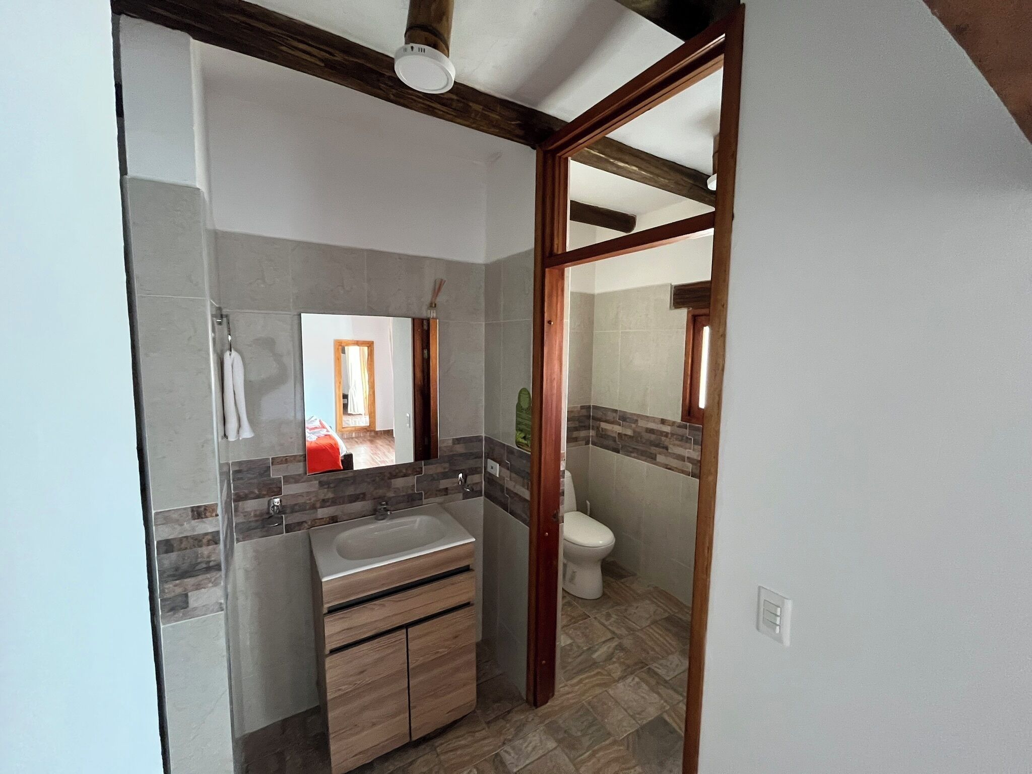 Een badkamer met een houten wastafelmeubel, een spiegel en een toilet.
