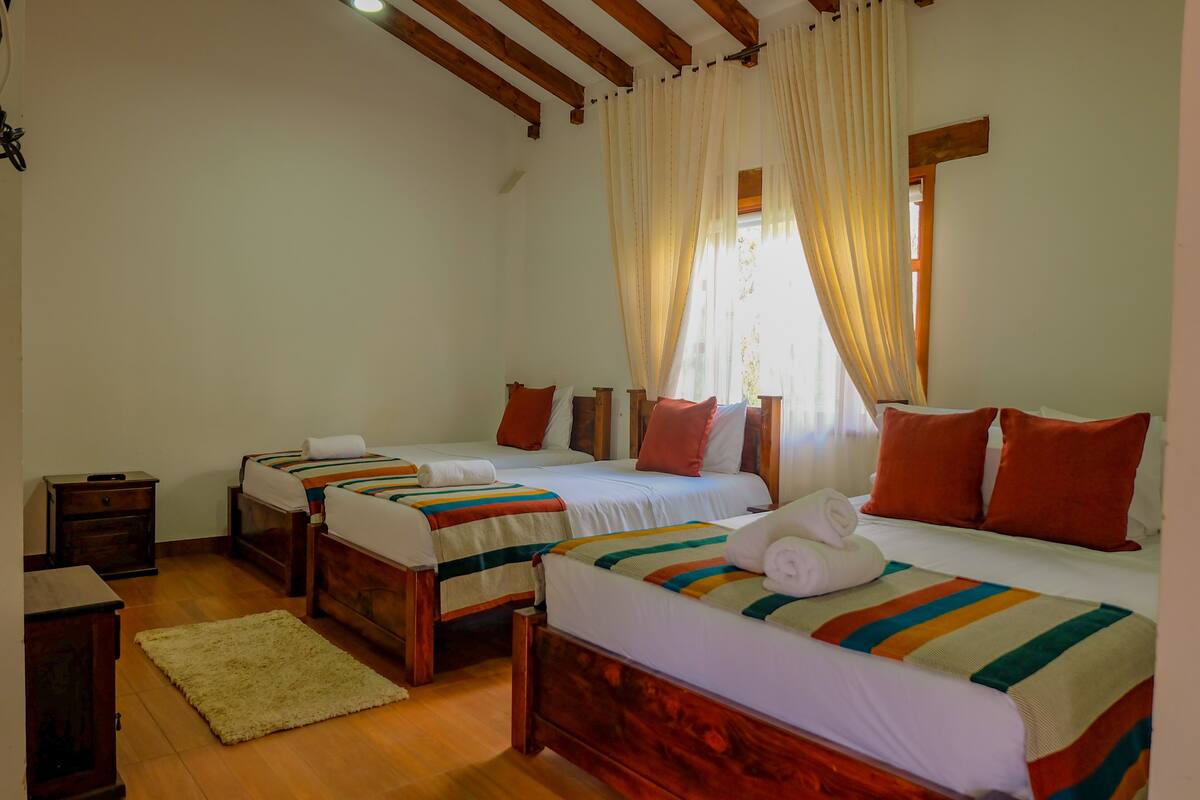 A hotel room with two beds, wooden headboards, white bedding, and a wooden floor.