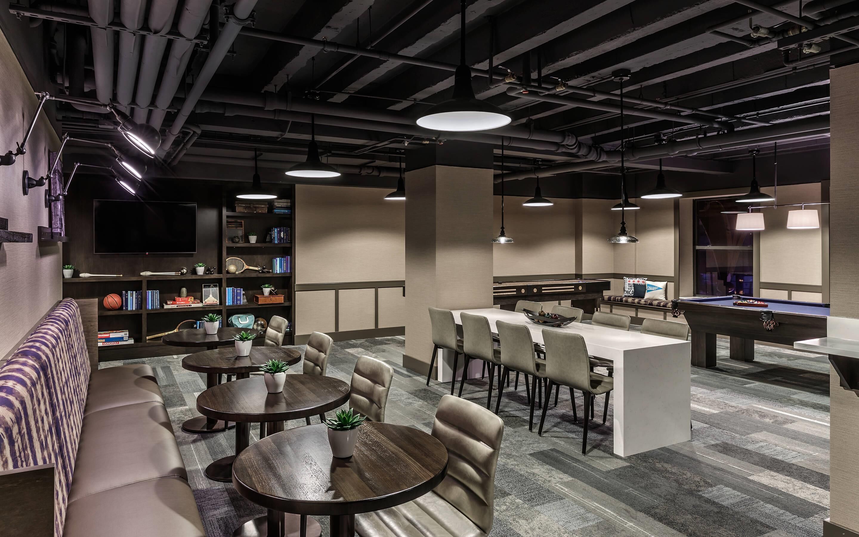 Un moderno área de lounge con diversas opciones de asientos, mesa de billar y bar.